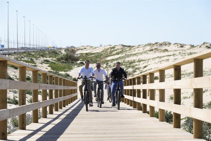 El presidente de la Junta de Andalucía, Juanma Moreno (i), montado en bicicleta, junto al alcalde de Cádiz, Bruno García (d); y el consejero de Sostenibilidad, Ramón Fernández Pacheco (c), inaugura el tramo de la ruta cicloturista Eurovelo 8 en Cádiz.