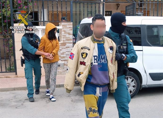 Dos de los arrestados salen de la vivienda junto a dos agentes especializados de la Guardia Civil