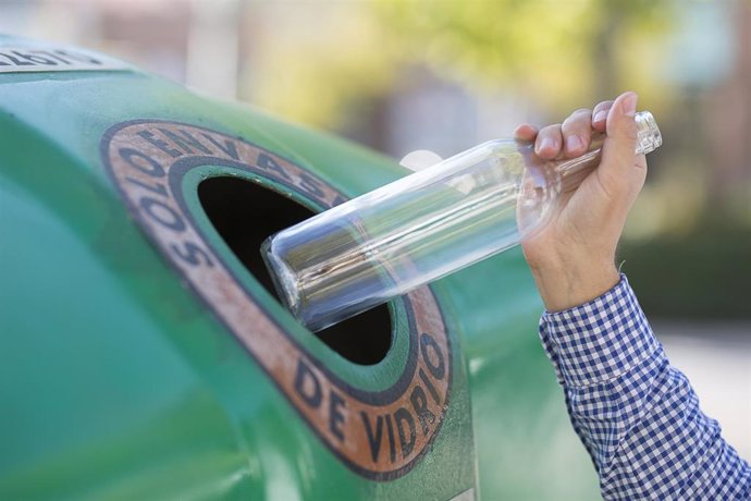 Archivo - Una persona deposita una botella de cristal en un contenedor de vidrio.