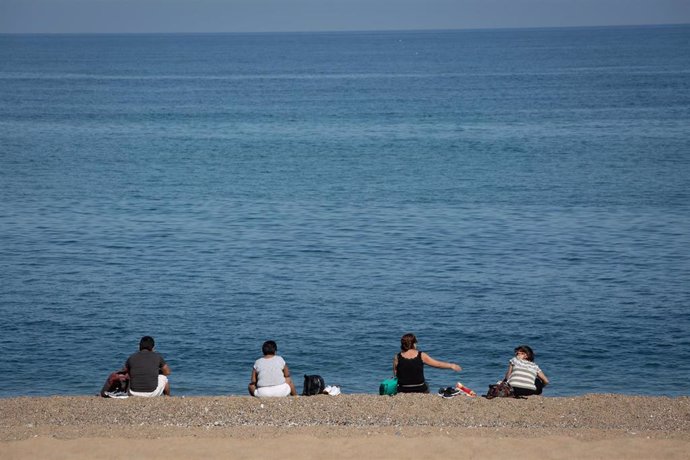 Imagen de archivo - Varias personas sentadas en la Playa de la Barceloneta de Barcelona