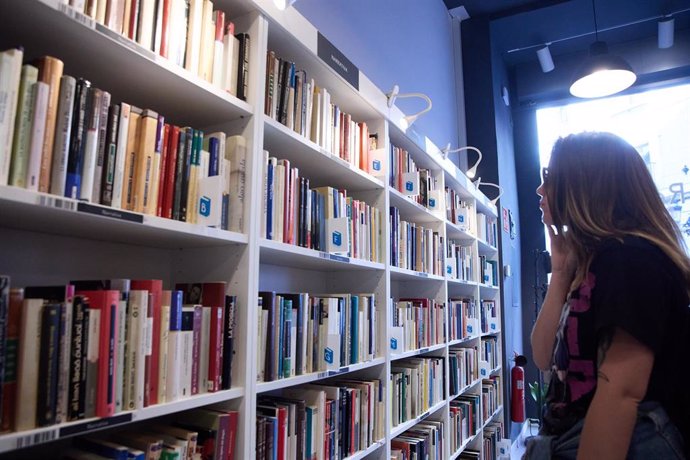 Archivo - Una mujer mira las estanterías en una librería madrileña.