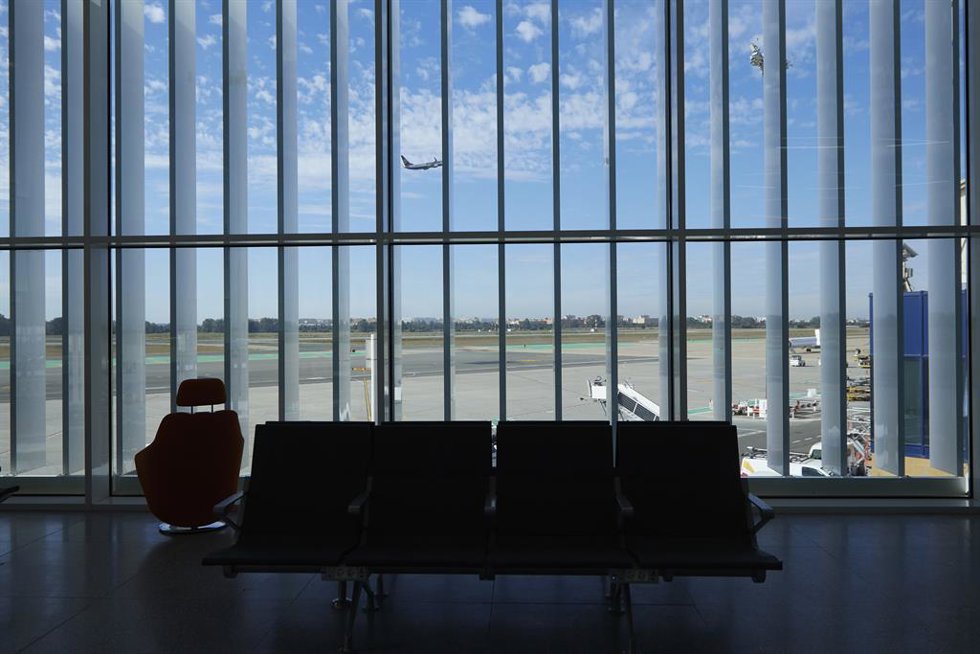 Archivo - Interior de la terminal del aeropuerto de Sevilla, con un avión que ha despegado al fondo.