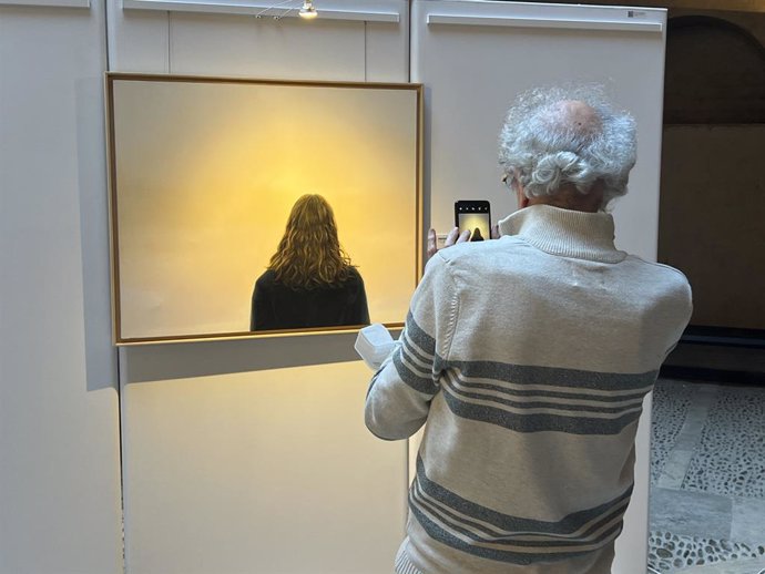 Una persona saca una foto a uno de los cuadros de la exposición 'Identidad', de la mexicana Catalina Orart .