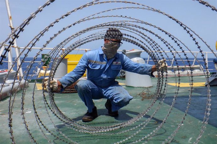 Archivo - Un marinero instala medidas de protección antipiratería en un carguero en el golfo de Adén 