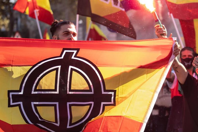Archivo - Un joven porta la bandera de España con un símbolo nazi impreso en ella durante una manifestación neonazi para celebrar el día de la Hispanidad, a 12 de octubre de 2021, en Barcelona.