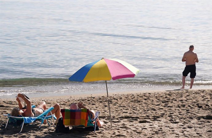 Archivo - Varias personas disfrutan tomando el sol en la playa de la Malagueta.