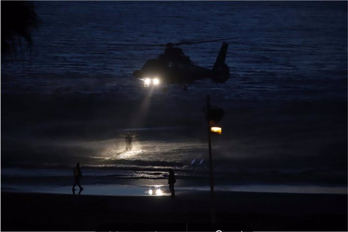Un helicóptero de Aduanas ilumina, aún en el agua, a un narcotraficante que intentaba huir tras frustrar un alijo de 400 kilos de hachís en la playa de Getares en Algeciras.