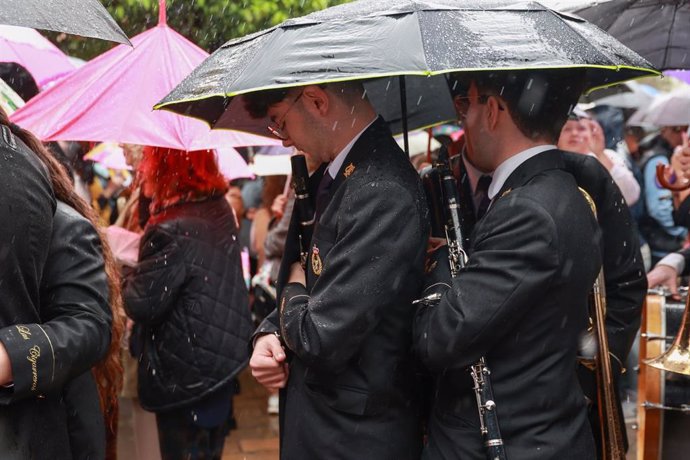 Músicos de la Hermandad del Cautivo de San Pablo se marchan tras suspenderse por la lluvia su estación de penitencia. A 24 de marzo de 2024, en Sevilla (Andalucía, España).