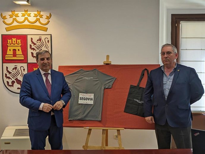 El delegado territorial de Segovia, José Luis Sanz Merino, con el presidente de Apadefim, Máximo Viloria, ante la camiseta y bolsa que se Entrega en las pruebas deportivas del 23 abril.