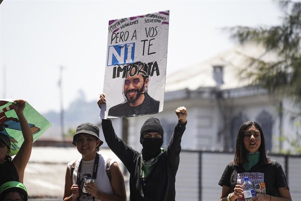 Archivo - Una manifestante en la concentración por el Día Internacional de la Mujer en San Salvador porta una pancarta en contra del presidente Nayib Bukele.