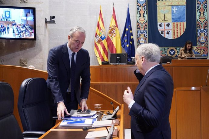 El presidente del Gobierno de Aragón, Jorge Azcón, conversa con el consejero de Fomento, Octavio López, antes del inicio de la sesión plenaria de las Cortes.