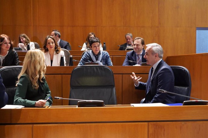 El presidente del Gobierno de Aragón, Jorge Azcón, habla con varios diputados del PP antes del inicio de la sesión plenaria de las Cortes autonómicas.