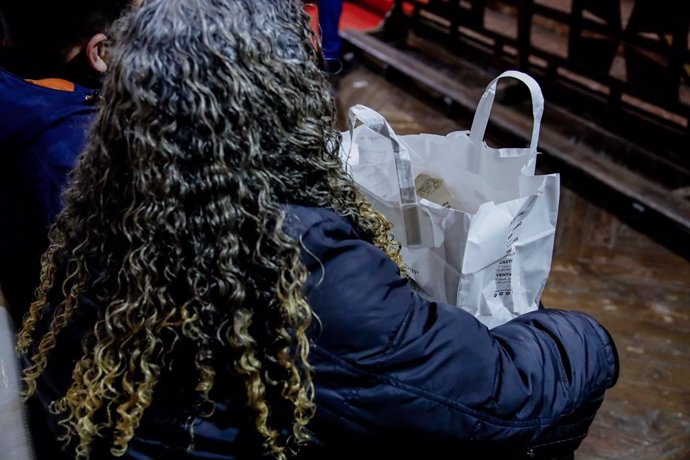 Archivo - Una mujer con una de las bolsas de comida preparadas por la ONG Mensajeros de la Paz para la de cena de Nochevieja, en la iglesia de San Antón del Padre Ángel, a 31 de diciembre de 2022, en Madrid (España). Por tercer año consecutivo la compañía