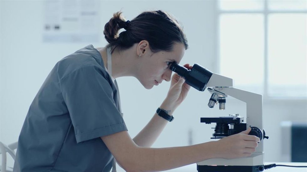 Archivo - Investigadora mirando por un microscopio