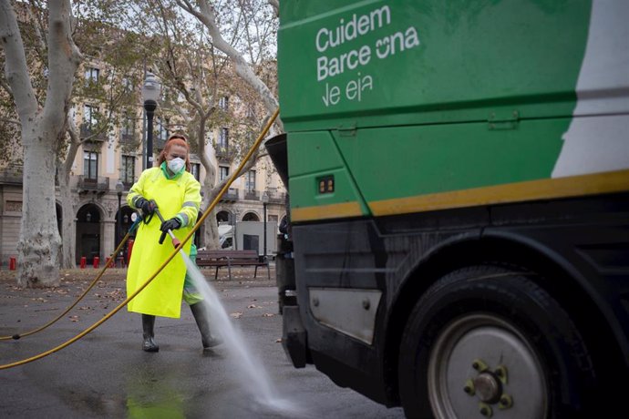 Archivo - Una trabajadora de la limpieza riega una calle con una manguera.