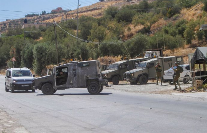 Archivo - 02 August 2023, Palestinian Territories, Jordan Valley: An Israeli military vehicle closes the street near the house where the perpetrator of a shooting attack was suspected to be inside. A gunman had opened fire at a passing car belonging to se