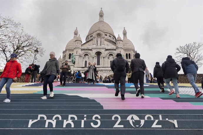 April 19, 2024, Paris, France, France: Paris, France April 19, 2024 - People walk up the stairs leading to the Sacre Coeur basilica decorated with a fresco in Olympic colors as part of the preparations for the Paris 2024 Olympic Games. Less than 100 days 