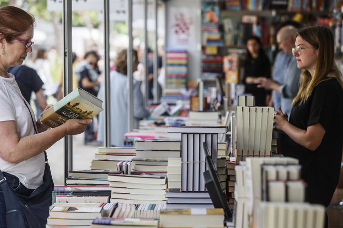 Archivo - Una mujer sostiene un libro en la Fira del Llibre de Valencia