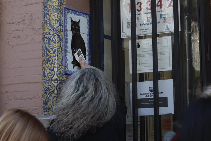 Archivo - Una persona frota un décimo de Lotería en Sevilla en imagen de archivo. 