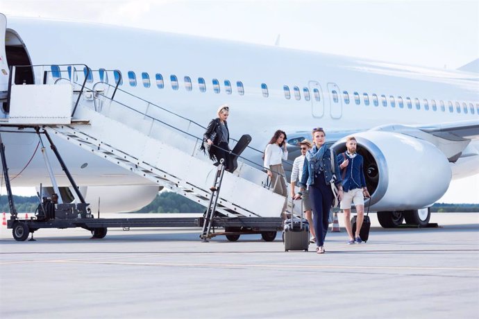 People disembarking a flight at commercial airport terminal. Group of people leaving the airplane.