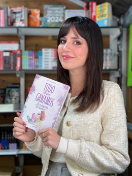 La escritora Emi Huelva sostiene el libro 'Todo lo que ganamos' en la Feria del Libro de Almería.
