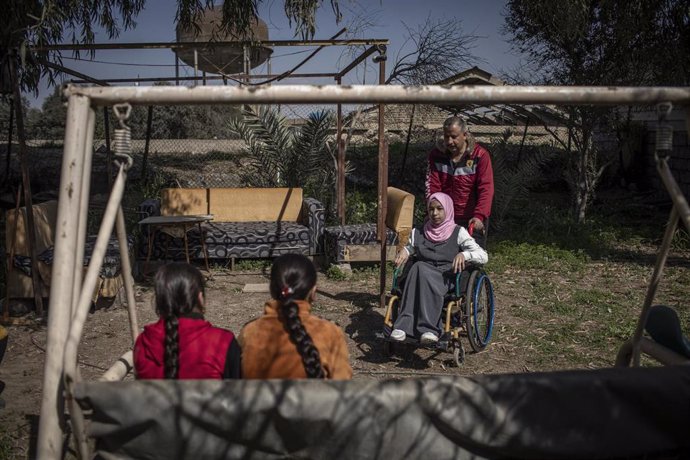Archivo - Una joven en silla de ruedas, víctima de armas explosivas, posa junto a su familia en Mosul, Irak.