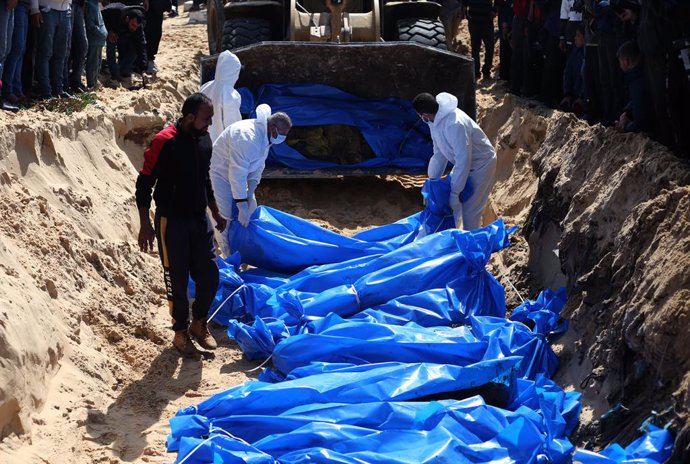 Archivo - Imagen de archivo de palestinos enterrando cuerpos en Gaza