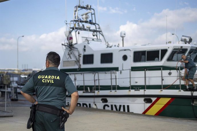 Archivo - Un agente de la Guardia Civil delante de una embarcación del Servicio Marítimo.