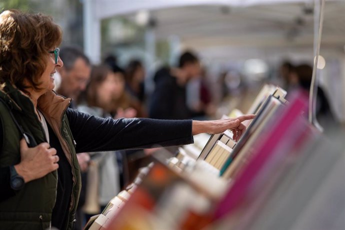 Varias personas miran libros en un puesto durante el día de Sant Jordi 2024, a 23 de abril de 2024, en Barcelona, Catalunya (España). Barcelona acoge como cada año la festividad de Sant Jordi y engalana la ciudad de rosas rojas. Además, la actividad princ