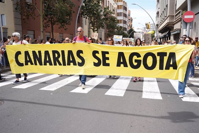 Varias personas protestan con una pancarta durante una manifestación contra el modelo turístico, a 20 de abril de 2024, en Santa Cruz de Tenerifei