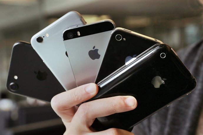 Archivo - FILED - 12 September 2017, Berlin: A young woman holds up Apple iPhones of different generations in Berlin. Photo: Fernando Gutierrez-Juarez/dpa-Zentralbild/dpa