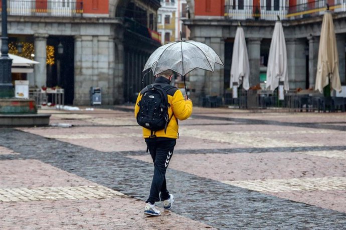 Archivo - Un hombre camina protegido por un paraguas el mismo día de la llegada del temporal ‘Gaetán’, en la Plaza Mayor de Madrid, (España), a 20 de enero de 2021. 