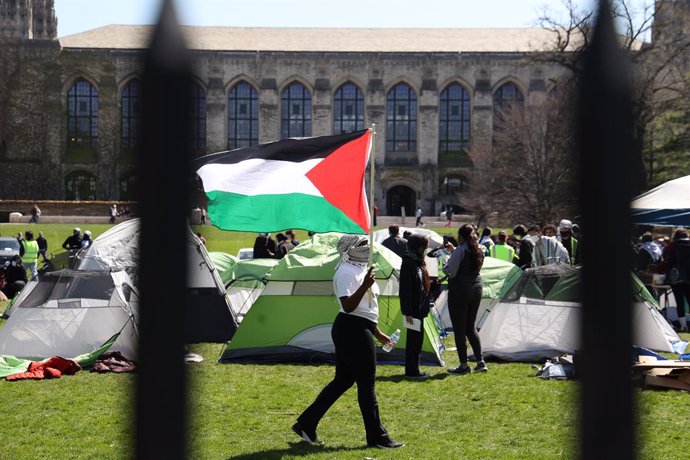 April 25, 2024, Evanston, Illinois, USA: A student waving a Palestinian flag walks among the tents in an encampment at Northwestern University. Students are demanding that Northwestern divest and stop supporting Israel.