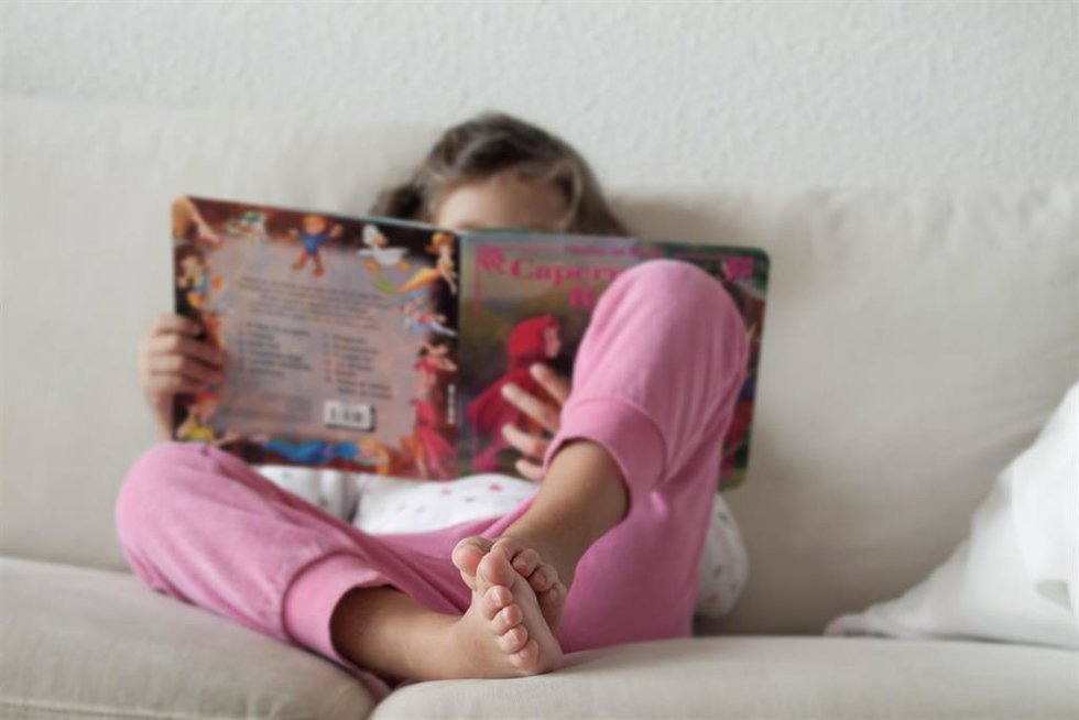Archivo - Una niña leyendo un cuento en su casa