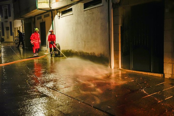 Bombeiros limpan a rúa de Vilaxoán de Arousa, en Vilagarcía de Arousa (Pontevedra), onde un home asasinou supostamente ao seu cuñado dunha puñalada na tarde deste venres, 26 de maio de 2024