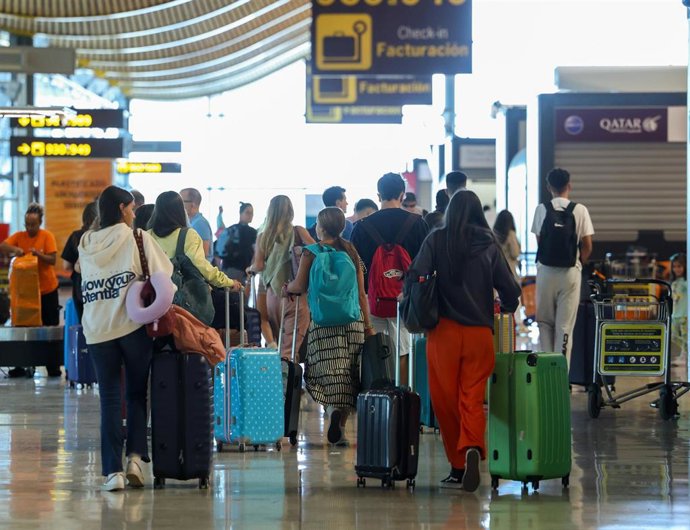 Archivo - Varias personas con maletas en el aeropuerto.