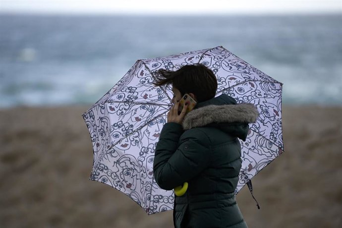 Archivo - Una mujer con un paraguas en el Paseo Marítimo de A Coruña donde se aprecia fuerte viento como consecuencia de la borrasca Barra, a 7 de diciembre de 2021, en A Coruña, Galicia (España). 
