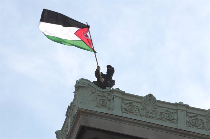 April 30, 2024, New York, United States: A pro-Palestine protester waves the Palestinian flag from the roof of Hamilton Hall at Columbia University. Pro-Palestine demonstrators rallied outside one of the entrances at Columbia .University in Manhattan, New