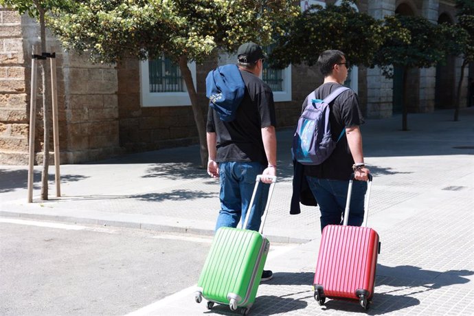 Dos turistas con sus maletas llegando a la ciudad de Cádiz.