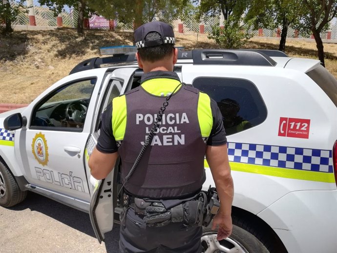 Archivo - Un agente de la Policía Local de Jaén junto a un vehículo oficial.