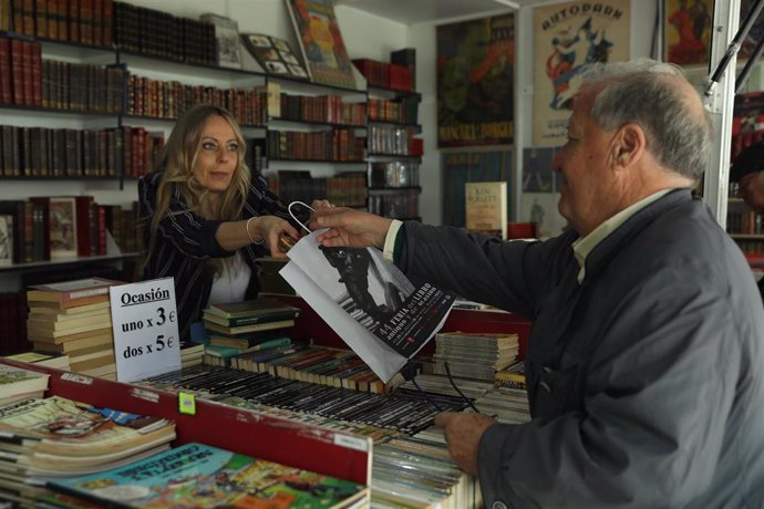 Archivo - Un hombre compra un libro en la Feria del Libro Antiguo, en el Paseo de Recoletos.