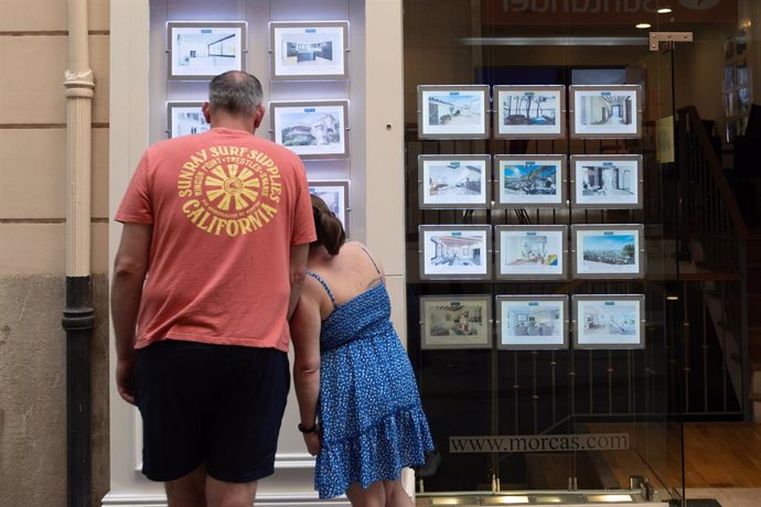 Dos personas observan los anuncios de viviendas en venta en una inmobiliaria, a 16 de abril de 2024, en Palma de Mallorca, Mallorca, Baleares (España). 