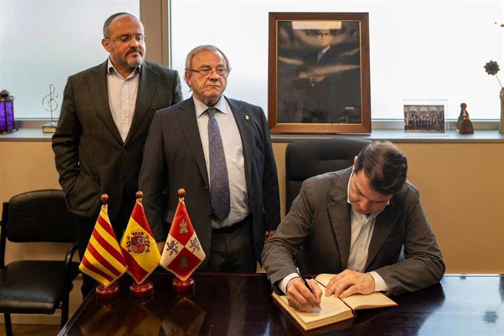 El candidato del PP a las elecciones catalanas, Alejandro Fernández (1i), mientras que el presidente de la Junta de Castilla y León, Alfonso Fernández Mañueco (1d), escribe en el libro de firmas del Centro Castellano Leónés de Barcelona