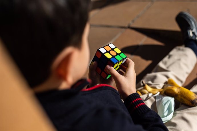 Archivo - Un niño juega con un cubo de rubik en el patio del Colegio Alameda de Osuna el día en que entra en vigor la medida que permite no utilizar mascarilla en los patios escolares de Madrid, a 25 de octubre de 2021, en Madrid, (España). Con este permi