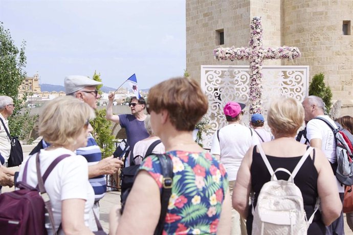 Archivo - Turistas junto a la Cruz de Mayo situada junto a la Torre de la Calahorra y el Puente Romano de Córdoba, en una imagen de archivo.