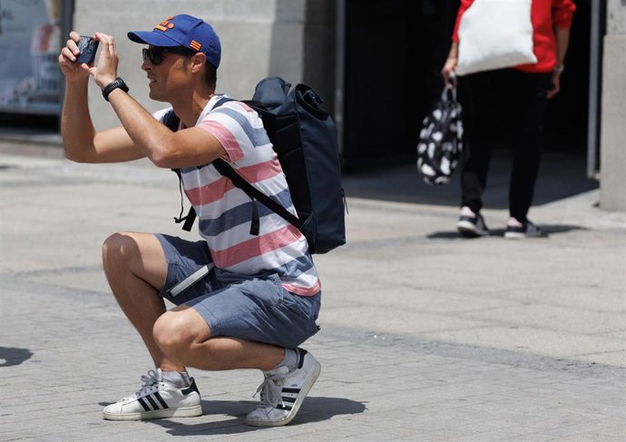 Archivo - Un turista toma fotografías en la Puerta del Sol
