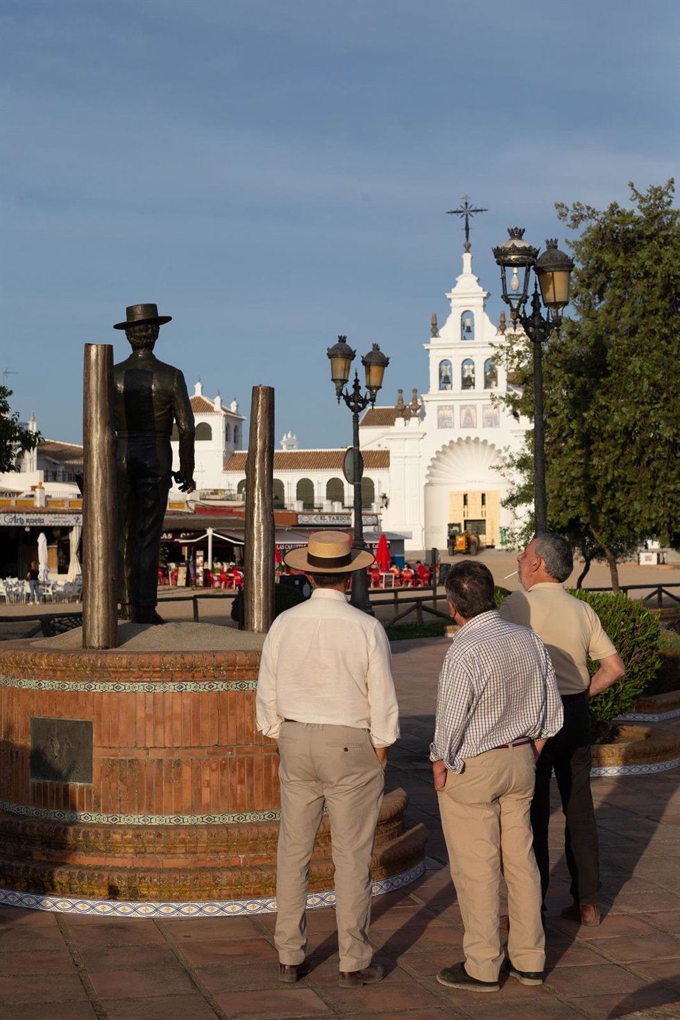 Archivo - Tres personas junto a la estatua del Tamborilero durante el fin de semana de la Romería del Rocio. Archivo.