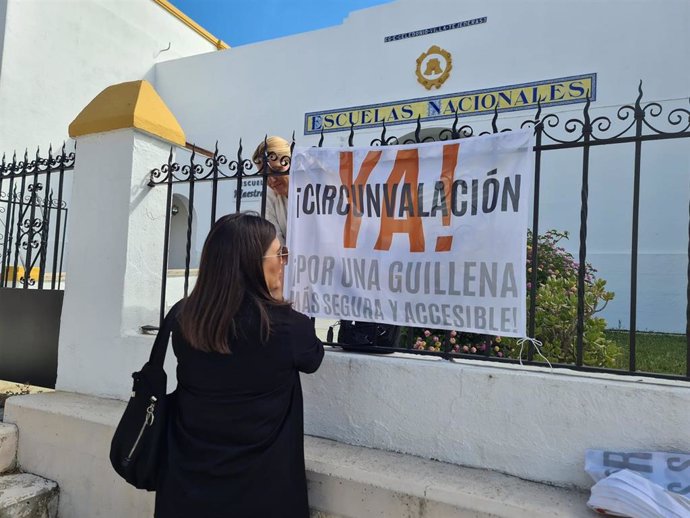 Una vecina pasa junto a una pancarta reivindicativa en la que se exige la construcción de una circunvalación en la localidad.