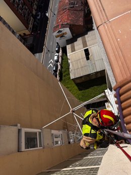 Uno de los bomberos, descendiendo por el sistema de cuerdas para acceder a la vivienda ubicada en un decimocuarto piso.