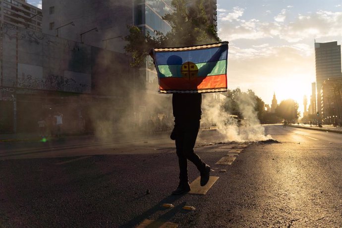 Archivo - Una persona porta la bandera mapuche durante unas protestas en Chile.